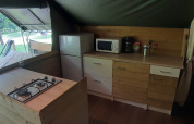 Coin cuisine dans la tente safari Kibo au camping Ushuaïa Villages Le Viaduc avec réfrigérateur et micro-ondes.