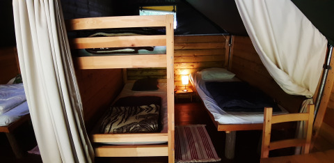 Inde i safariteltet Kibo på Campsite Ushuaïa Villages Le Viaduc i Frankrig, med køjesenge og hyggelig belysning.