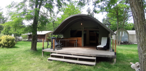 Safari-teltet Kibo med træterrasse på Campsite Ushuaïa Villages Le Viaduc, omgivet af grønne træer i Frankrig.