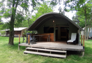 Safari-teltet Kibo med træterrasse på Campsite Ushuaïa Villages Le Viaduc, omgivet af grønne træer i Frankrig.