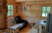 Accogliente interno in legno del Ranch Chalet al Campeggio Ushuaïa Villages Le Viaduc con divano e tavolo da pranzo.