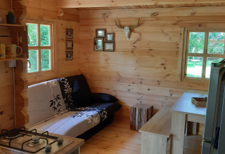 Gemütliches Holzinterieur im Ranch Chalet, Campsite Ushuaïa Villages Le Viaduc, mit Sofa und Esstisch.