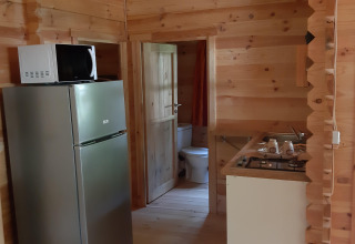 Interno del Ranch Chalet a Ushuaïa Villages Le Viaduc con cucina, frigorifero, microonde e pareti in legno.