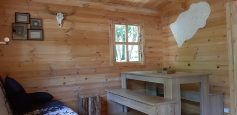 Interno in legno del Ranch Chalet al campeggio Ushuaïa Villages Le Viaduc, con tavolo, panca e decorazioni.