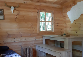 Holzinterieur der Ranch Chalet im Ushuaïa Villages Le Viaduc Campingplatz, mit Tisch, Bank und Dekor.