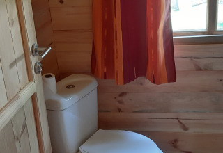 Toilet in a wood-paneled bathroom with a window and curtain at Ranch Chalet, Ushuaïa Villages Le Viaduc in France.