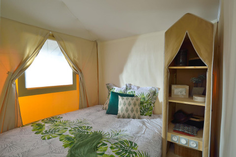 Slaapgedeelte in safaritent 'Jungle Lodge' op Campsite Ushuaïa Villages Le Viaduc in Frankrijk met bladmotief decor.