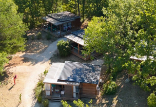 Aerial view of wooden cabins at Campsite Le Luberon surrounded by trees in Provence-Alpes-Côte d’Azur, France.