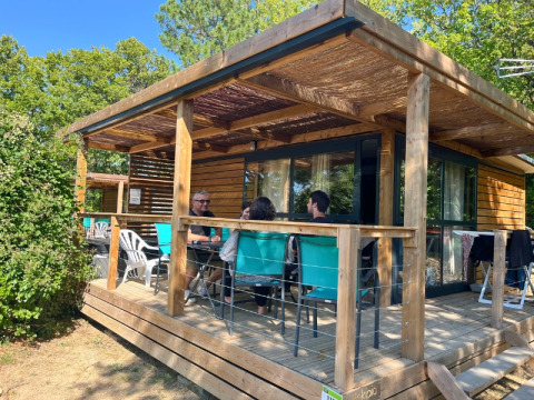 People relaxing on the wooden terrace of a cabin at Campsite Le Luberon in Provence-Alpes-Côte d’Azur, France.