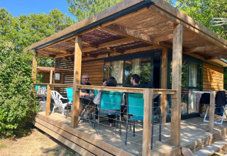 Persone sedute sulla veranda in legno di un bungalow al campeggio Le Luberon in Provenza, Francia.