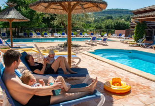 Famiglia rilassata a bordo piscina al campeggio Le Luberon in Provenza-Alpi-Costa Azzurra, Francia.