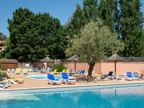 Area piscina del campeggio Le Luberon in Provenza-Alpi-Costa Azzurra con sdraio e alberi intorno.
