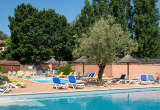 Area piscina del campeggio Le Luberon in Provenza-Alpi-Costa Azzurra con sdraio e alberi intorno.