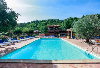 Piscina all'aperto con lettini e alberi al campeggio Le Luberon in Provenza-Alpi-Costa Azzurra, Francia.