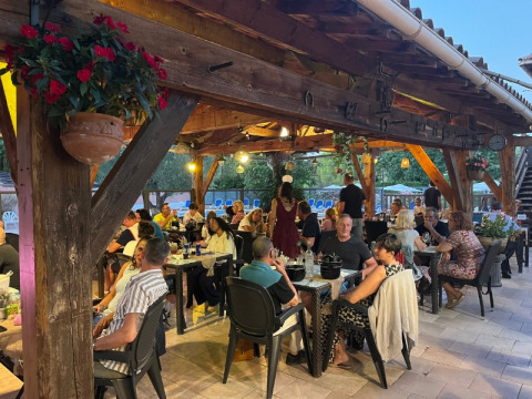 Vacanciers dînant et discutant sur la terrasse ombragée du camping Le Luberon en Provence, France.