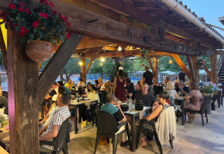 Vacanciers dînant et discutant sur la terrasse ombragée du camping Le Luberon en Provence, France.