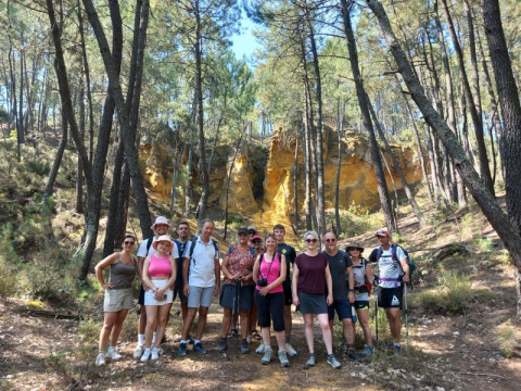 Un groupe de randonneurs pose devant des falaises ocres et des pins au camping Le Luberon en Provence.