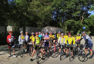 Un groupe de cyclistes pose avec leurs vélos sous les arbres au camping Le Luberon, en Provence, France.