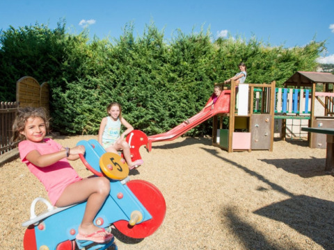 Des enfants jouent sur une aire de jeux avec toboggan et bascule au camping Le Luberon, sud de la France.