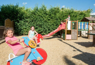 Des enfants jouent sur une aire de jeux avec toboggan et bascule au camping Le Luberon, sud de la France.