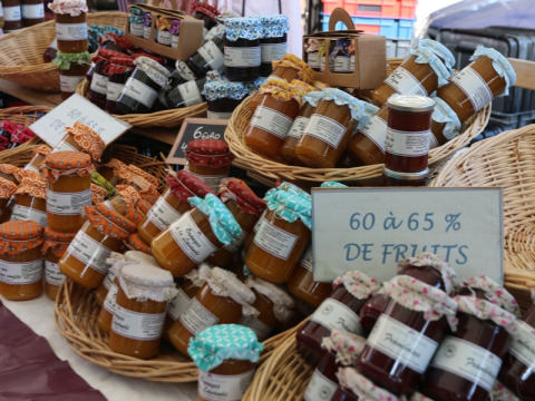 Un stand de marché avec des pots colorés de confiture maison, vendus dans un camping en Provence, France.
