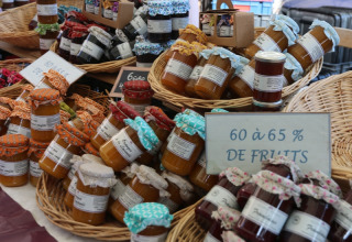 Un stand de marché avec des pots colorés de confiture maison, vendus dans un camping en Provence, France.