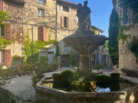 Une jolie fontaine en pierre sur une place pavée du camping Le Luberon en Provence-Alpes-Côte d’Azur.