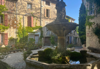 Une jolie fontaine en pierre sur une place pavée du camping Le Luberon en Provence-Alpes-Côte d’Azur.