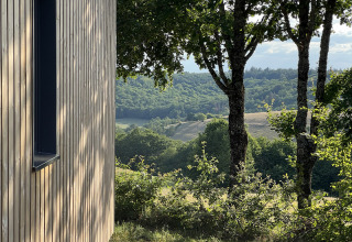 Vista dalla Lodge al campeggio La Nouvelle Croze in Francia, con alberi e verdi colline sullo sfondo.