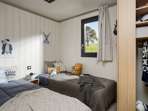 Cozy lodge bedroom with two single beds, window with outdoor view, and modern decor accents.
