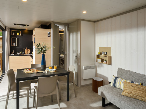 Modern lodge interior at Campsite La Nouvelle Croze in France featuring a dining area and kitchenette.