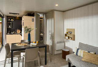 Modern lodge interior at Campsite La Nouvelle Croze in France featuring a dining area and kitchenette.