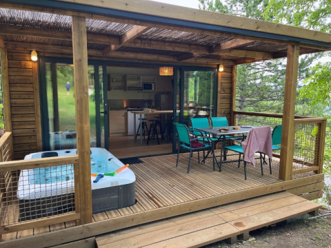 Cottage ‘Pantaïa’ al campeggio Le Luberon in Francia, con veranda coperta, vasca idromassaggio e tavolo da pranzo.