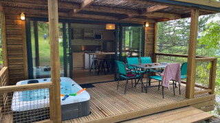 Cottage ‘Pantaïa’ al campeggio Le Luberon in Francia, con veranda coperta, vasca idromassaggio e tavolo da pranzo.
