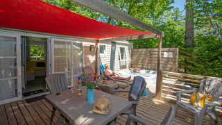 Buitenterras van Cottage Romarin op Camping Le Luberon, Frankrijk, met jacuzzi en zitplaatsen.