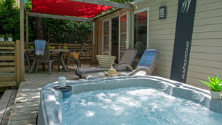 Outdoor deck with hot tub, sun loungers, and dining table at Cottage Romarin, Campsite Le Luberon, France.