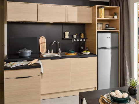 Cocina moderna en Lodge on stilts del camping La Nouvelle Croze en Francia, con gabinetes de madera y detalles negros.