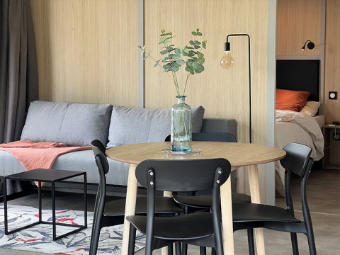 Intérieur de lodge moderne avec table à manger, canapé et chambre visible, au camping La Nouvelle Croze en France.