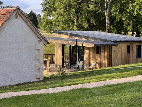 Foto de un lodge sobre pilotes en el camping La Nouvelle Croze en Francia, rodeado de césped y árboles verdes.