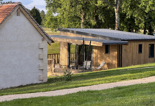 Photo of a stilt lodge at Campsite La Nouvelle Croze in France, with a wooden terrace and green scenery.