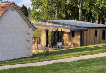 Photo of a stilt lodge at Campsite La Nouvelle Croze in France, with a wooden terrace and green scenery.