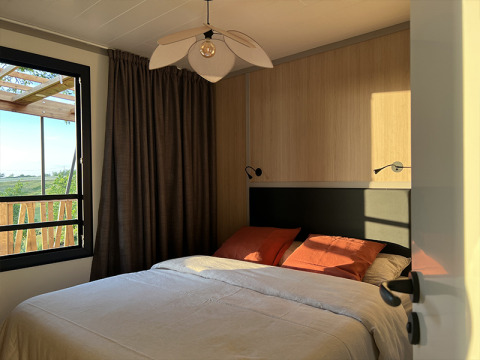 Bedroom at Lodge on Stilts at Campsite La Nouvelle Croze, France, with sunlight streaming through window.
