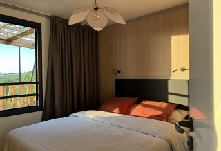 Chambre du Lodge on Stilts au camping La Nouvelle Croze, France, baignée par la lumière du soleil.