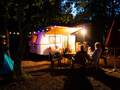 Abendliche Campingszene im Domaine des Chênes Blancs, Provence, mit Wohnwagen und bunten Lichtern.