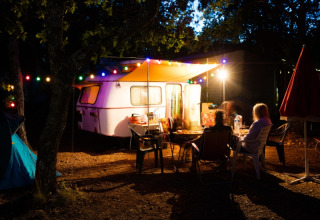 Abendliche Campingszene im Domaine des Chênes Blancs, Provence, mit Wohnwagen und bunten Lichtern.