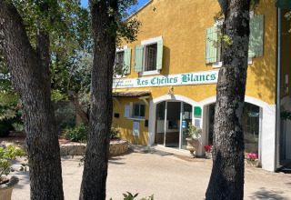 Entrée du Domaine des Chênes Blancs, parc de vacances en Provence-Alpes-Côte d’Azur, France, avec des arbres devant.