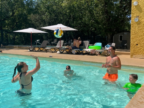 Gezin speelt met strandbal in zwembad van Domaine des Chênes Blancs, onder de zon in de Provence.