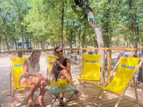 Twee vrouwen genieten op Ricard-stoelen bij Domaine des Chênes Blancs in Provence, Zuid-Frankrijk.