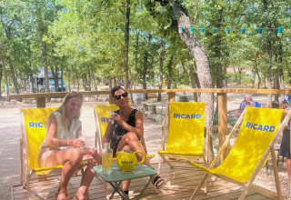 Deux femmes détendues sur des chaises Ricard jaunes au Domaine des Chênes Blancs en Provence, France.