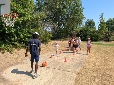 Children join an outdoor basketball activity with an instructor at Domaine des Chênes Blancs, Provence, France.